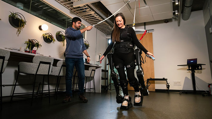 Eine gelähmte Frau macht erste Schritte mit dem Exoskelett